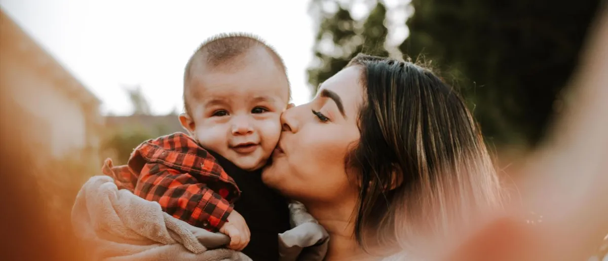 A mom kissing the cheek of a baby