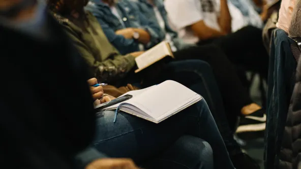 Students with textbooks on their laps sitting in a classroom